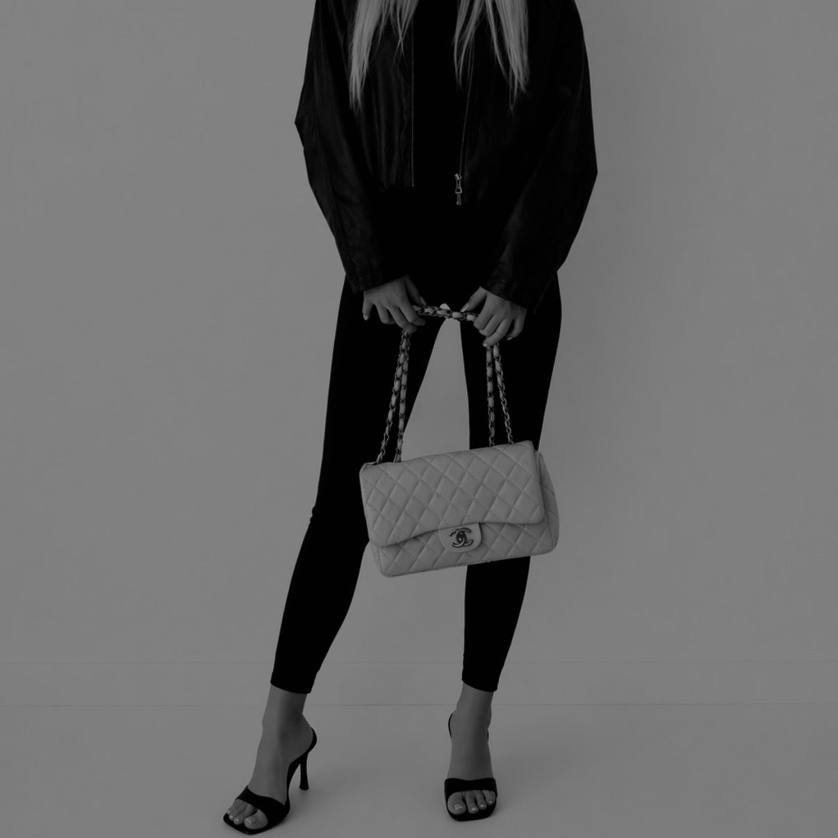 Person holding a quilted handbag against a plain background